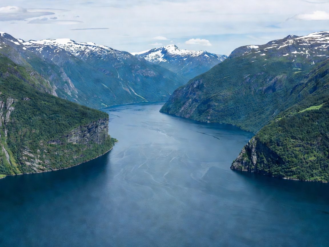 Expansive blue waters of Sognefjord framed by steep green peaks and distant snowfields